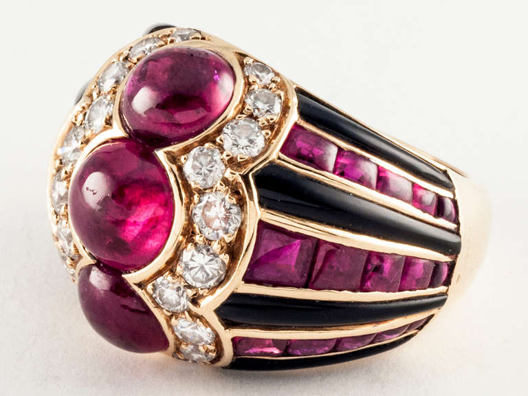 18 kt. gold ring set with black enamel and buff top rubies, centering 3 cabochon rubies, flanked by  round diamonds. Signed BULGARI 750. In original leather box.