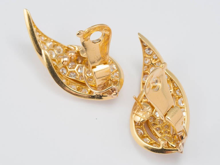 18 kt. gold ear clips set with circular cut diamonds set in sculptured gold plaques of a foliate design. Signed FRED , PARIS.