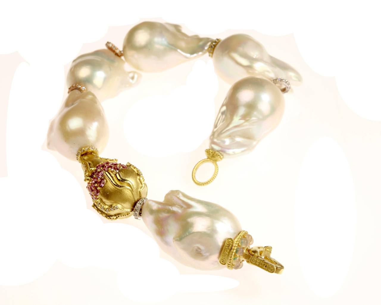 Baroque Pearl Bracelet with 18K Gold Rondel and Pink sapphires & Diamonds by Stambolian

0.92 ct. G Color, VS Clarity diamonds

1.44 ct.'s of Pink sapphires

In between each pearl is a diamond loop showing the separation between each pearl 

Hook