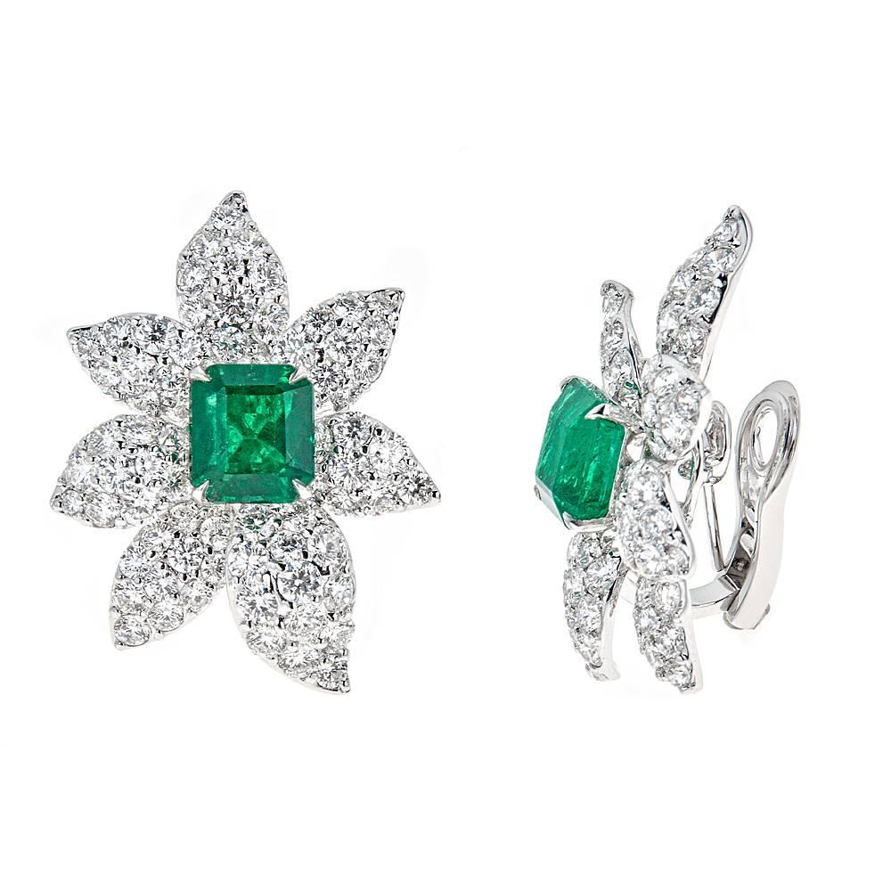 These radiant, florally inspired 18K White Gold earrings feature two center emerald cut Emeralds with a combined weight of 5.00 carats. Surrounding the center stones in a delicate petal design are 7.09 carats of brilliant white Diamonds. 

Features: