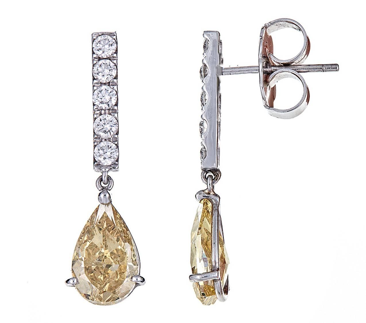 A pair of beautifully crafted 18k white gold earrings. 
1.16 carats of round white diamonds set the stage for two magnificent, pear shaped, fancy brown/yellow and yellow diamond drops.
Each diamond drop respectively weights 2.03 and 2.01 carats.