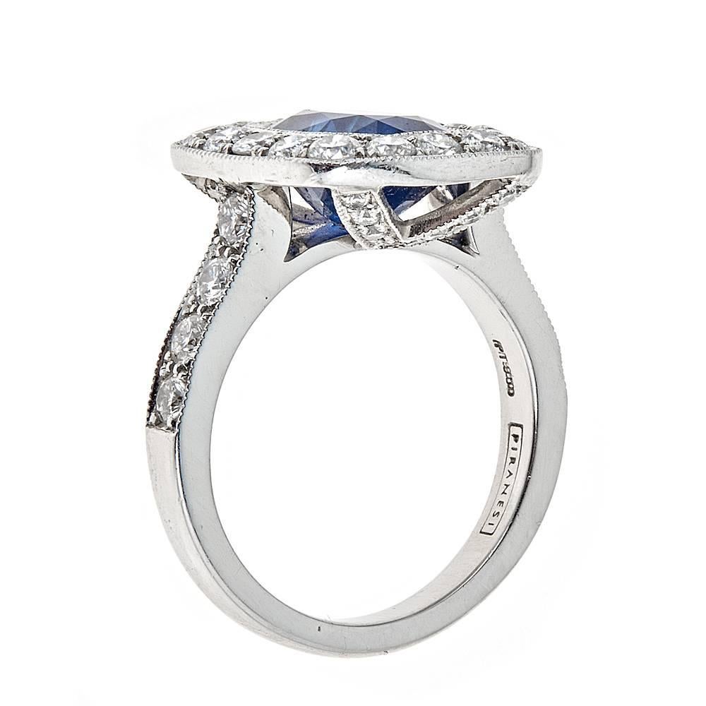 A striking platinum ring showcasing a 4.09 carat, GIA Certified, oval Blue Sapphire. This brilliant, multidimensional sapphire is accented by a Diamond set bezel and band, with a modern and sleek pave detailing on the back for a total Diamond weight