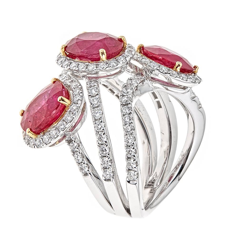 A magnificently designed 18K White and Yellow Gold cocktail ring. Three brightly colored Rubies, with a combined carat weight of 7.87, are artfully stacked in a soft descending pattern. Accented by 1.62 carats of round Diamonds in intricately laid