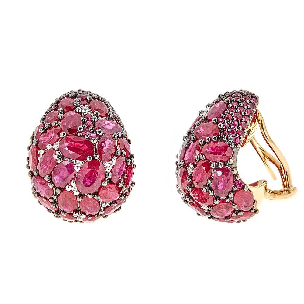 Remarkable 35.88 carat Ruby earrings. With their singular style, these earrings feature numerous round and oval shaped rubies in deep and vibrant red. With 0.14 carats of accentuating white diamonds, these rare pieces are set in a combination of 18K