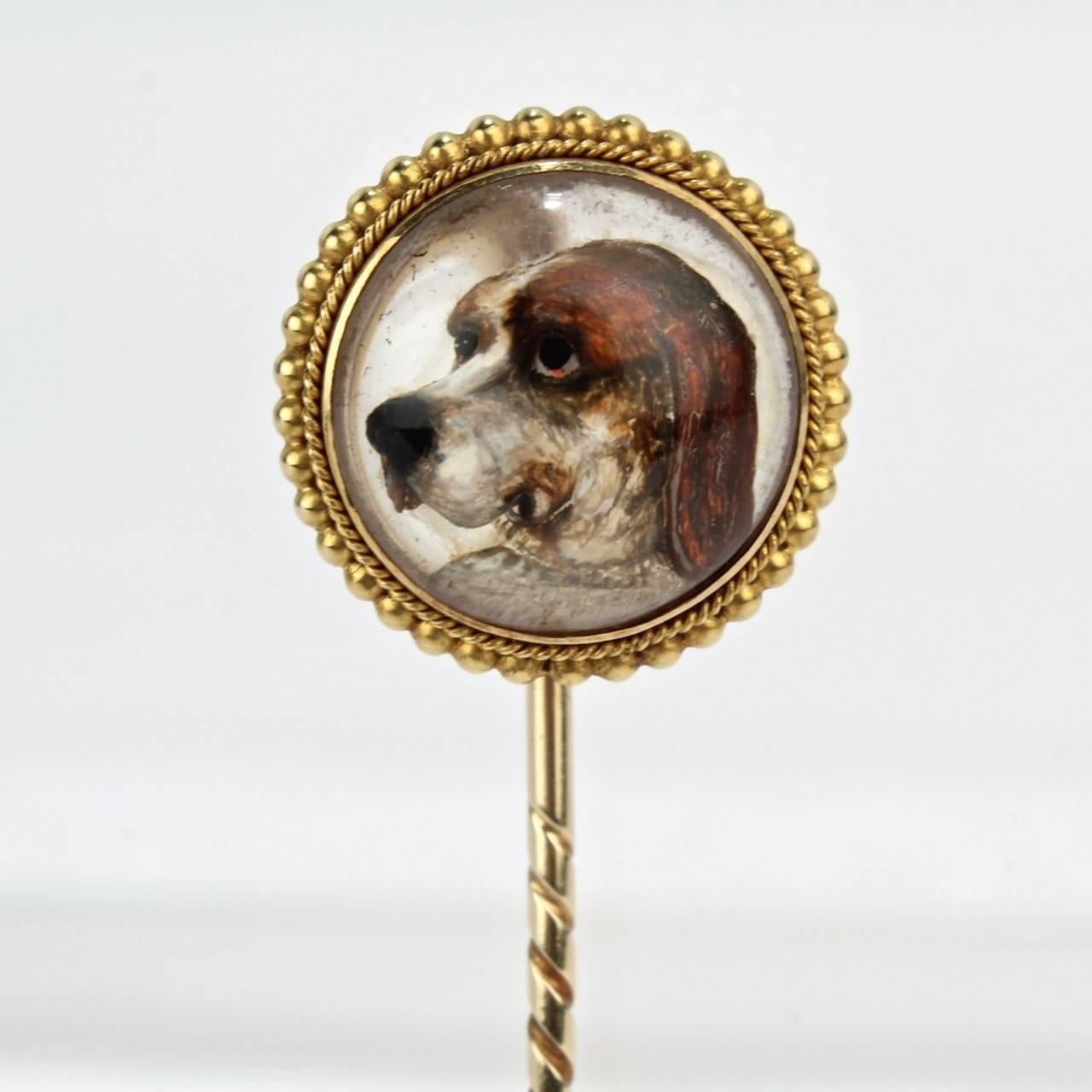 A good essex crystal and gold stick pin with a depiction of a beagle dog's head in three-quarter profile.

The convex crystal surrounded in a beaded mount. 

Width: ca. 3/4 in.
Length: ca. 3 1/8 in.

Items purchased from David Sterner Antiques must