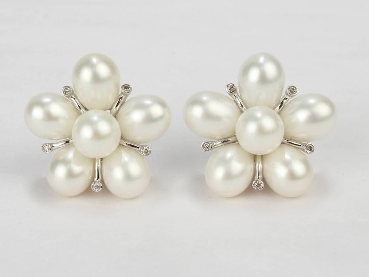 A fine pair of pearl and diamond cluster clip-on earrings set in the form of a flower.

Set in 14K white gold.

Diameter: ca. 7/8 in.

Items purchased from this dealer must delight you. Purchases may be returned for any reason for a period of seven