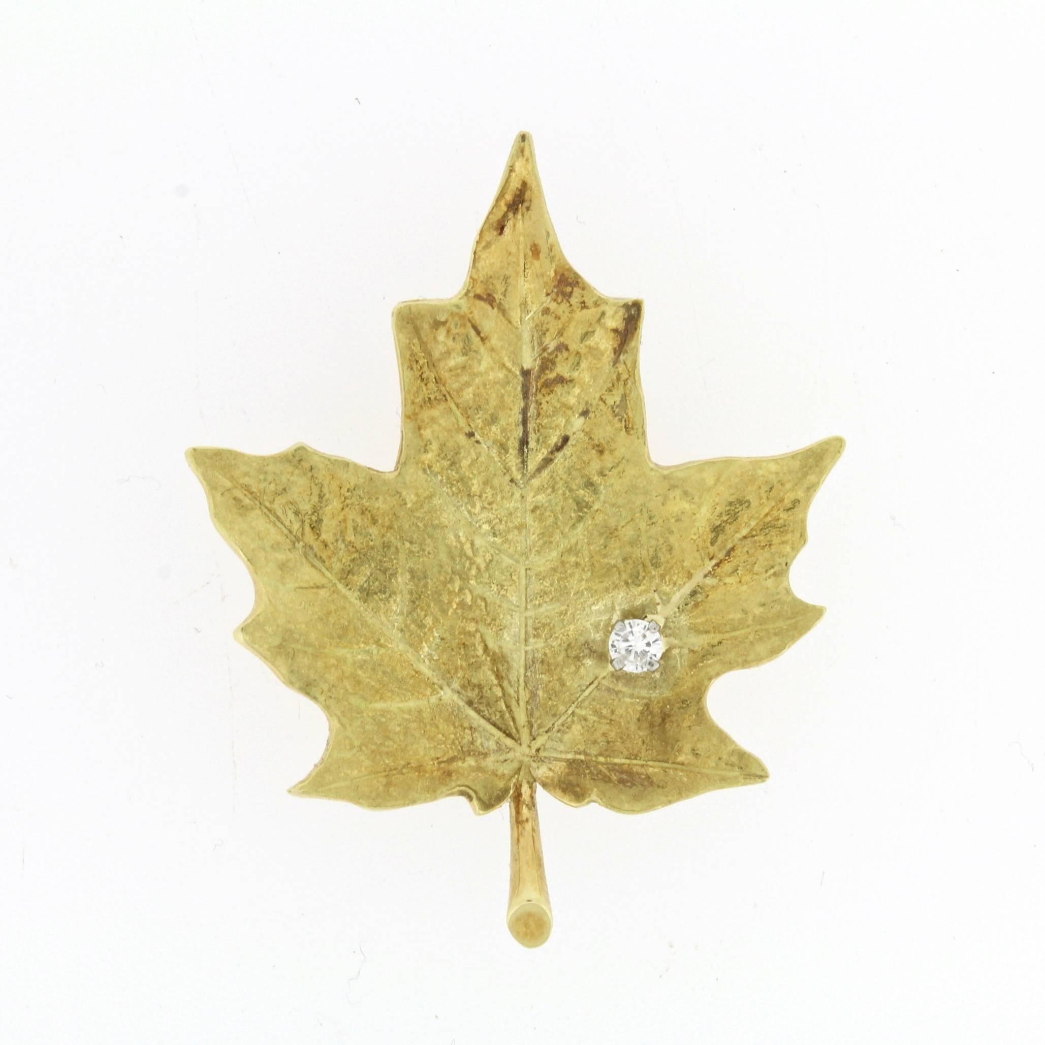 A very fine 18-karat yellow gold and diamond pin or brooch.  

Designed and produced by McTeigue in the early to mid-20th century.  

Of crisp maple leaf form with a veined, burnished surface set with a small high-quality accent diamond. 

The