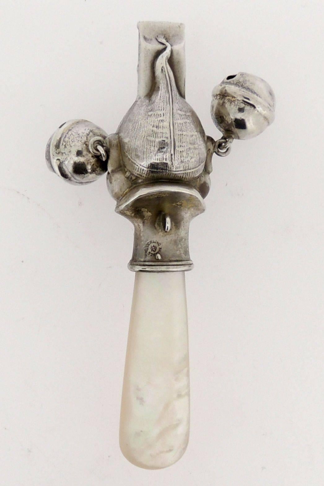 An Unger Bros. sterling silver & mother of pearl handled baby rattle and whistle. 

The rattle depicts the face of a Palmer Cox Brownie character's head with pink-dyed mother of pearl inset eyes. 

An incredibly rare form that is amongst the most