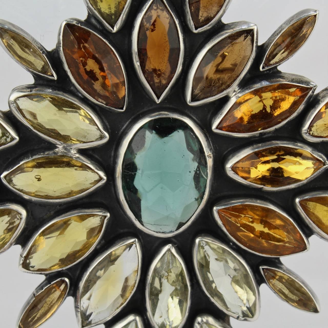 A fine vintage Federico Jimenez sterling silver brooch or pin. 

Of a star shape with a central aquamarine gemstone and an array of surrounding citrine gemstones. There are traces of foil backs to some of the gems (noticeable on the reverse).

The