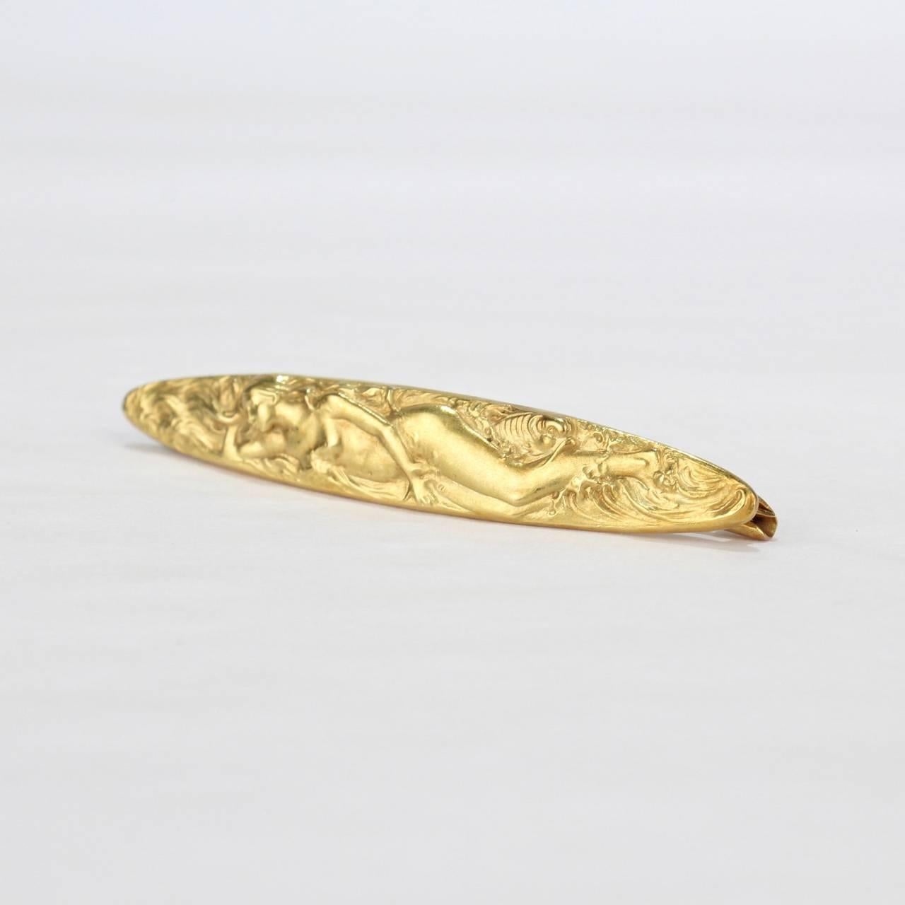 A fine signed Kremnetz 14-karat gold American Art Nouveau period pin or brooch. 

Of horizontal lozenge form with a finely worked repousse reclining nude. She appears to be in a dream (possibly an allegory to sleep or a depiction of a Venus) and