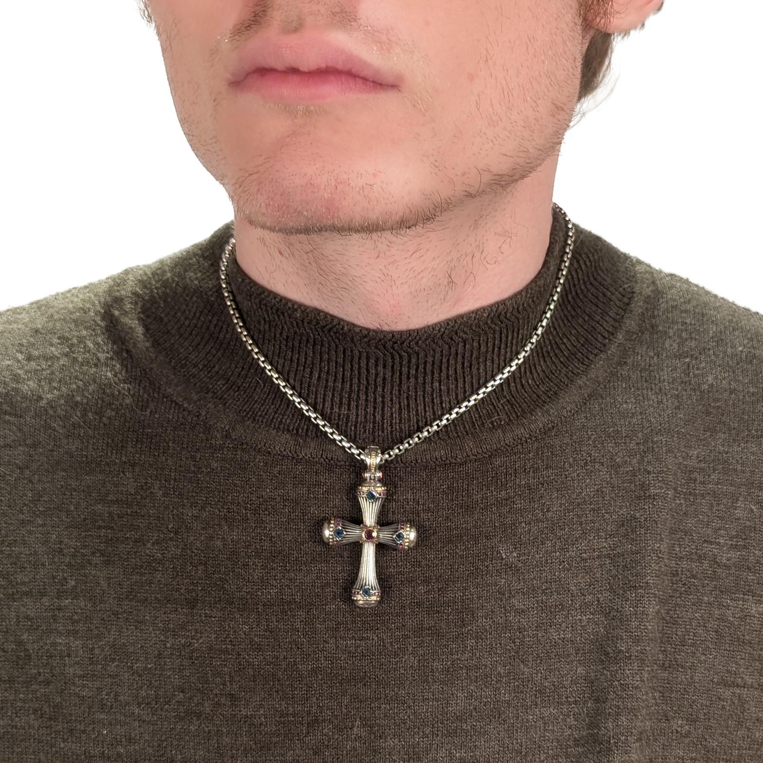 Un beau pendentif en forme de croix, signé.

Par Konstantino.

De la série Delos.

En argent sterling avec des accents en or jaune 18 carats. 

Serti d'une topaze bleue de Londres de taille carrée et d'une bande de petits saphirs roses en serti clos