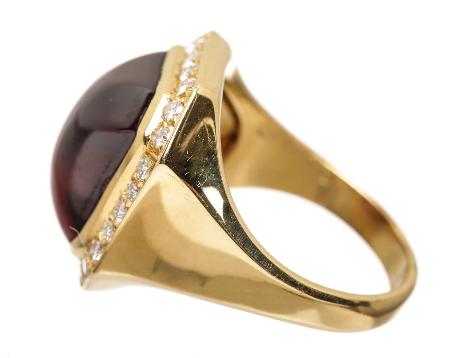 Crafted from 18k yellow gold, this ring is surrounded by diamonds and a large cabochon garnet. The garnet weighs approximately 8.16 carats.  Approximately .51 carats of diamonds.