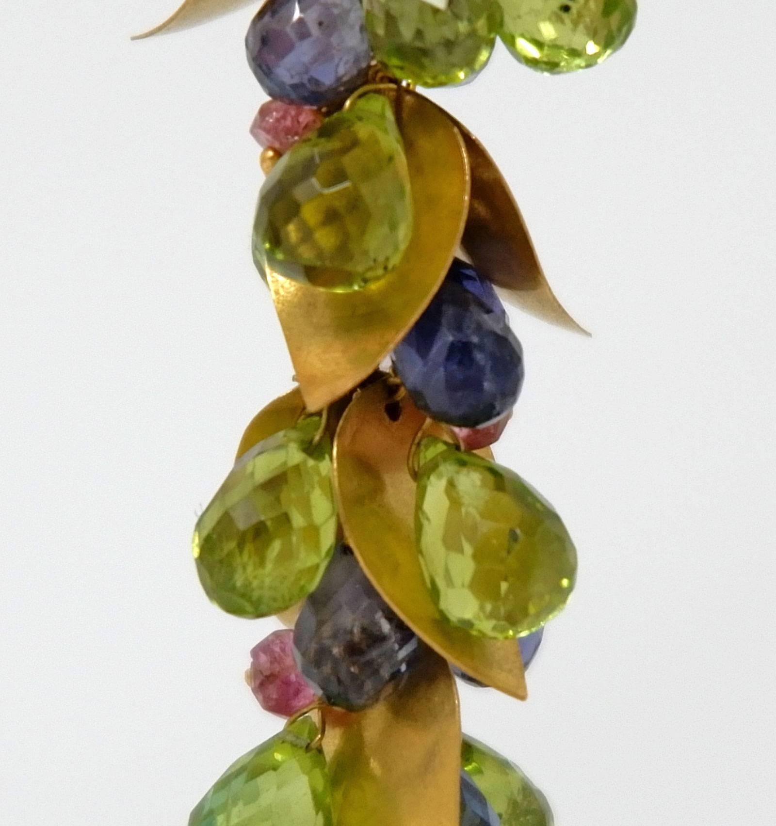 A pair of delicate hand crafted earrings with two large topaz briolettes which are suspended below a cluster of  gorgeous faceted beads consisting of peridots, iolites, tourmalines and 18 Karat matte gold leaves. Wear these jewels easily day as well