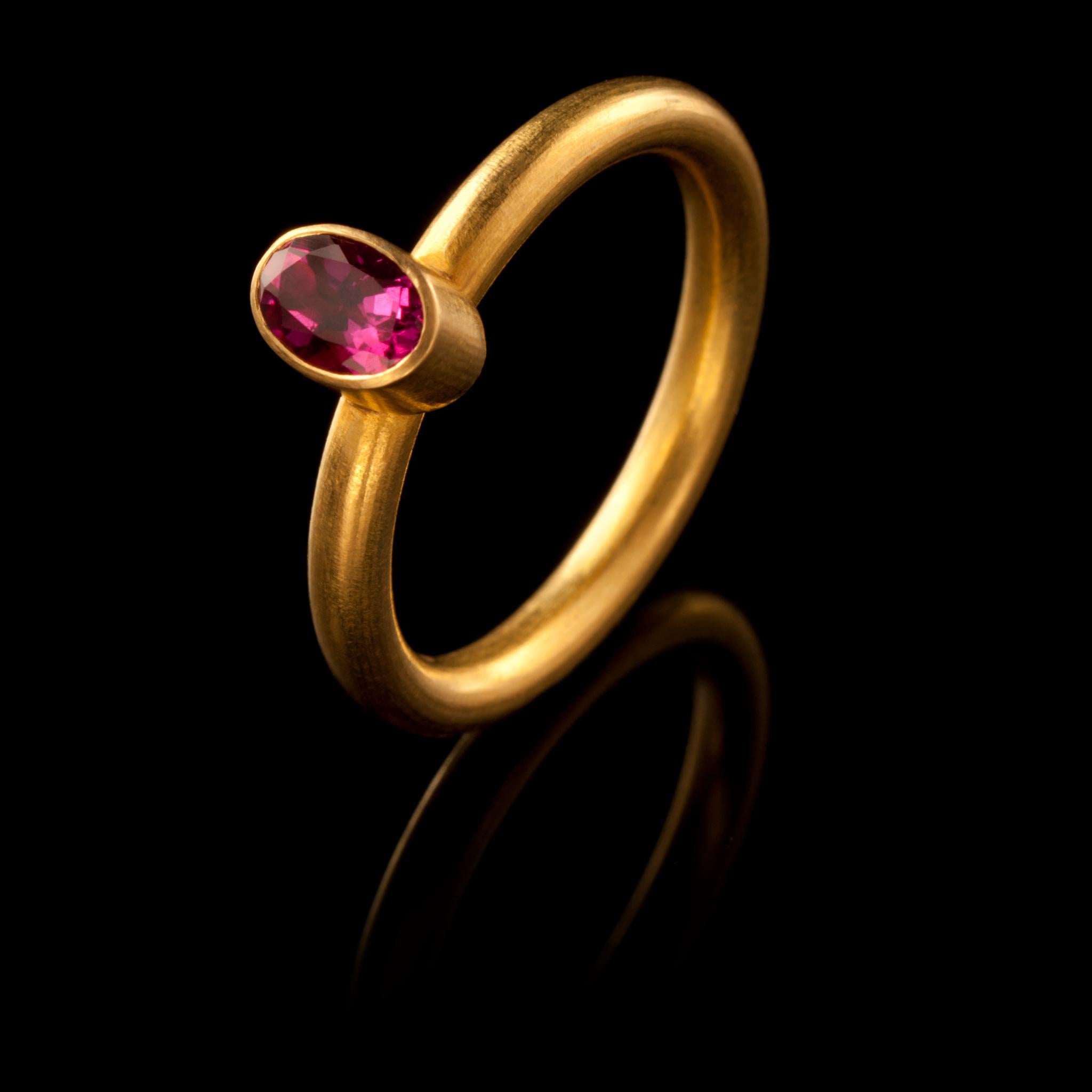 A chic, hand crafted 18 karat matte gold stacking ring with an oval, faceted hot pink tourmaline. Size: UK O/P, US 7.6, Europe: 56.5. The ring can be resized. Wear it on its own or with other rings from the collection as shown on our model.