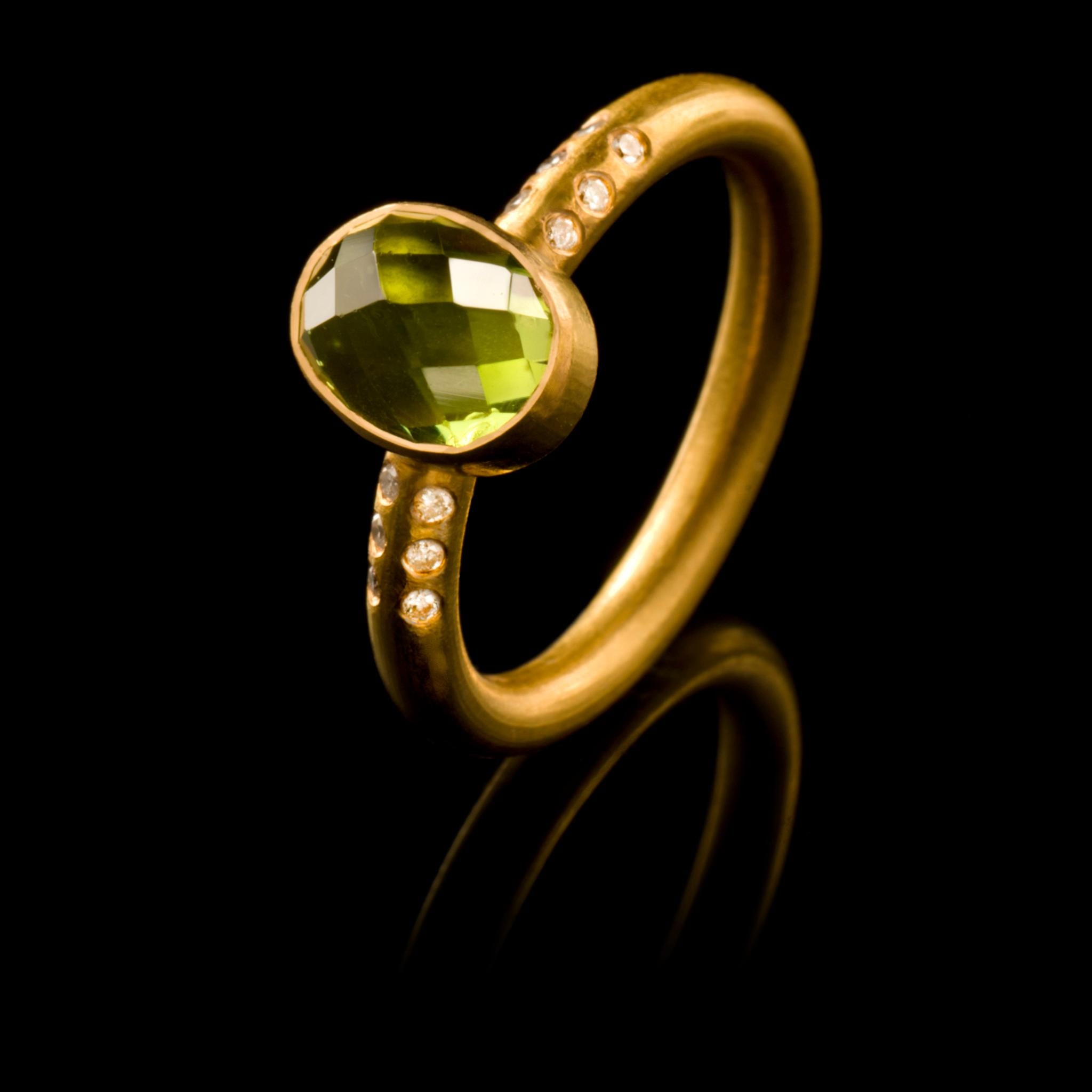 A chic, hand crafted 18 karat matte gold stacking ring with an oval cut peridot flanked by six diamonds either side. Size: UK O/P US 7.5 EUROPE 55.5 The ring can be resized. Wear it on its own or with other rings from the collection as shown on our