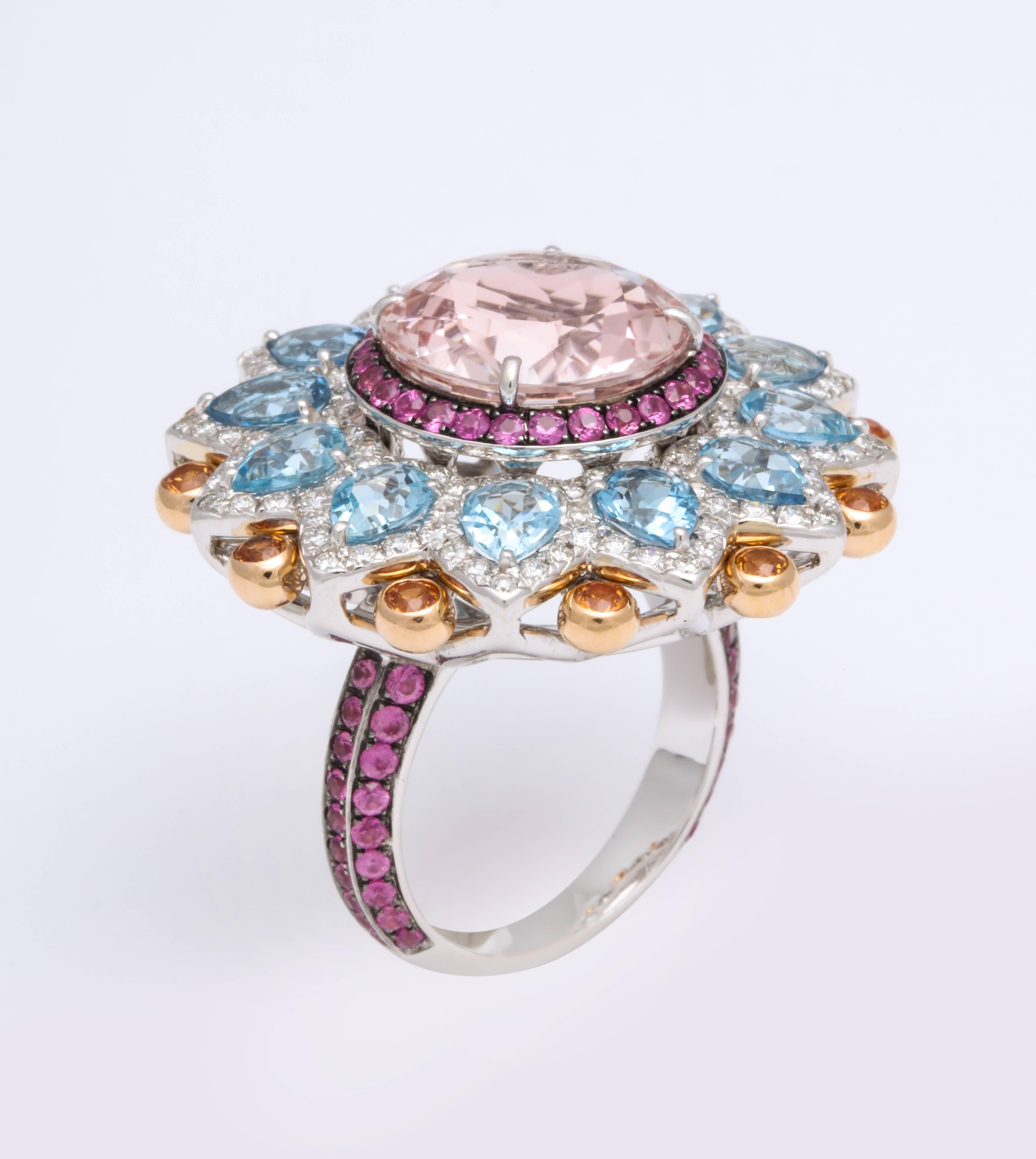 18K White Gold, Kaleidoscopic configuration Ballerina ring mounted with central pink champagne Kunzite in a round pink Sapphire halo, with gently sloped radiating pear shaped Aquamarine, and round brilliant cut orange Sapphires, framed within a