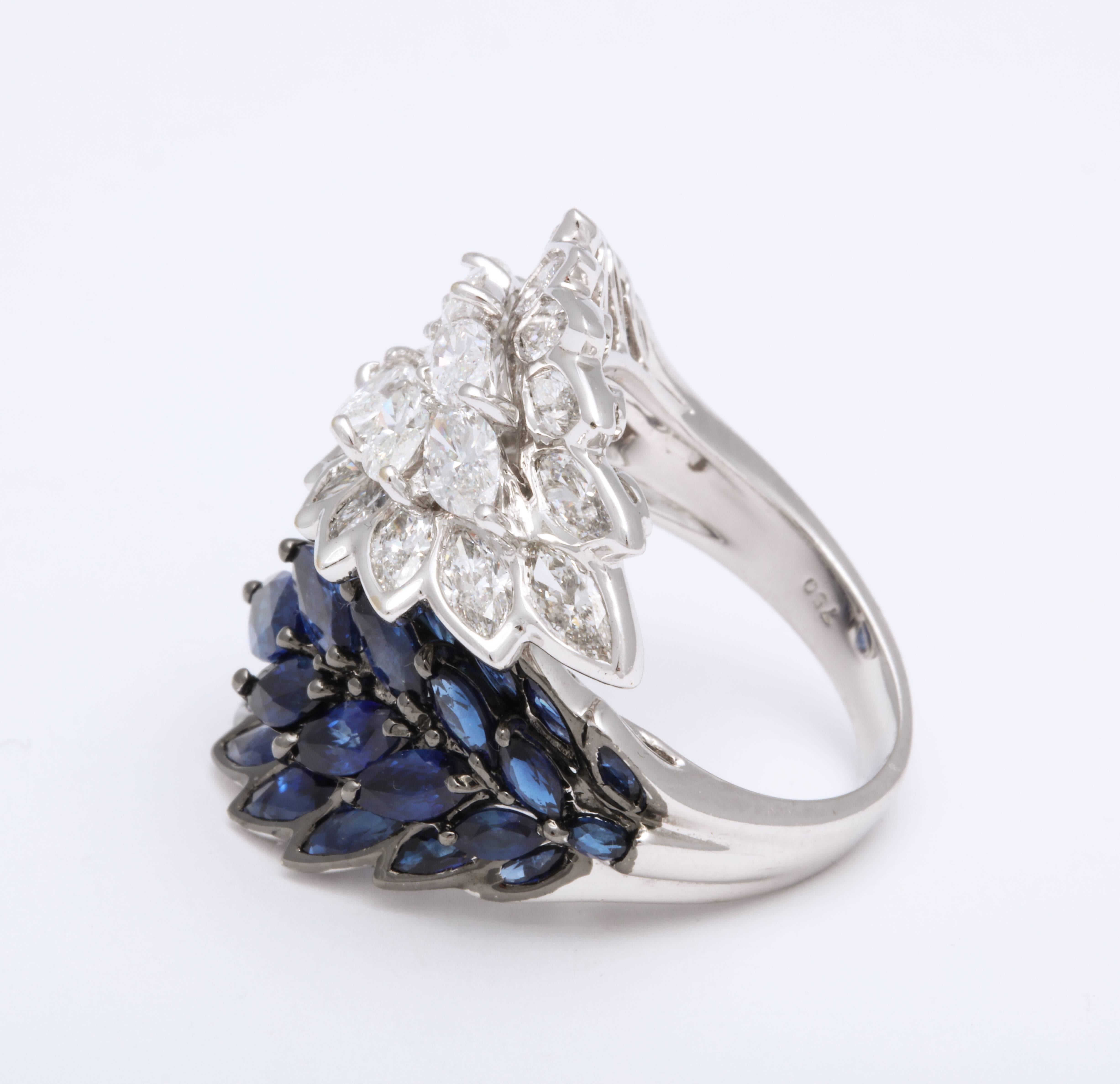 Set in 18K White Gold this is a very imaginative and stylized by-pass ring decorated with marquise shape white diamond scales flaring in one direction weighing4.42 carats, and royal blue marquise shape Sapphires scales wrapping around the opposite