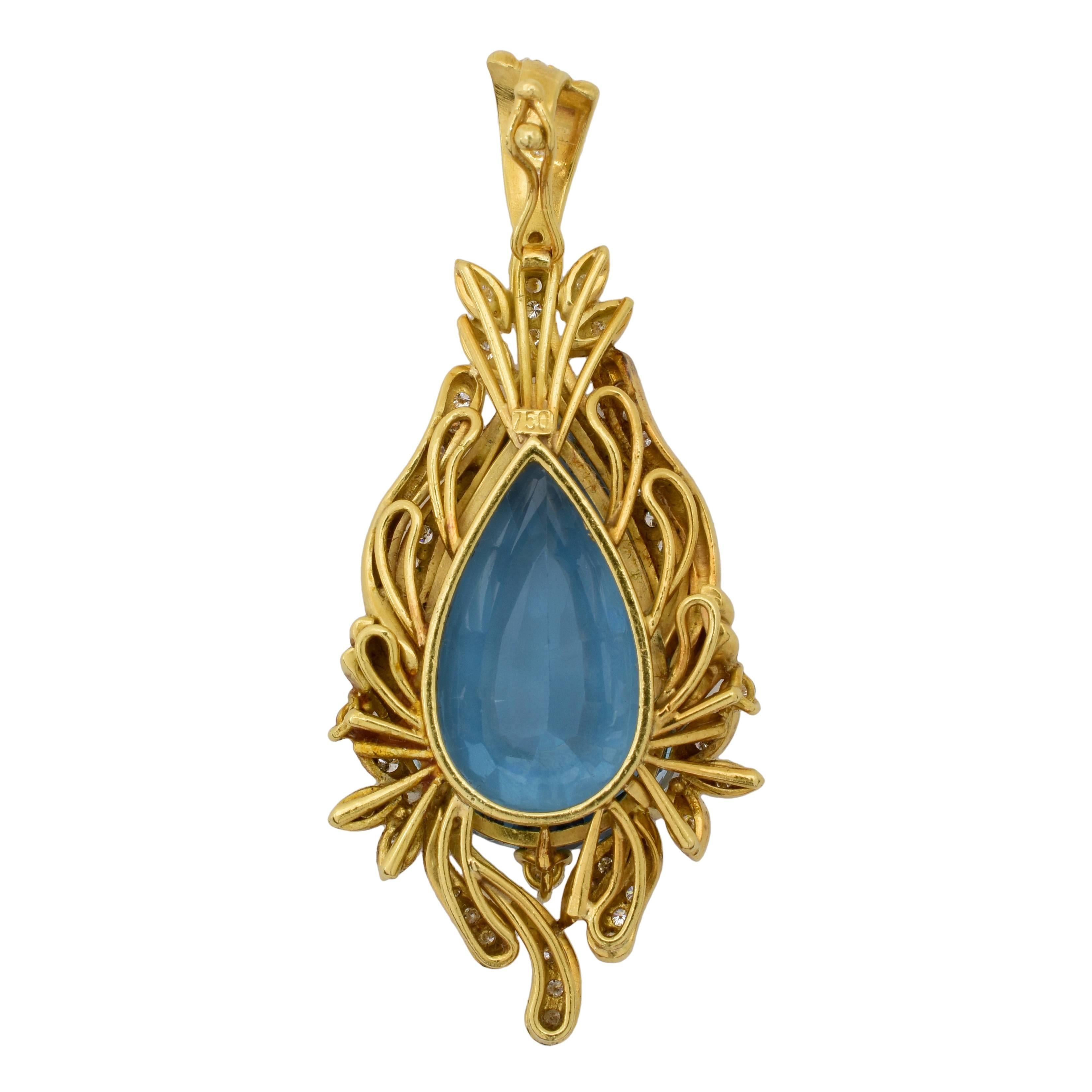This 1940's pendant features an approximately 15 carat pear shape blue topaz center stone, accented by approximately .40 carats of diamonds, in a floralesque 18k yellow gold Retro mounting. 