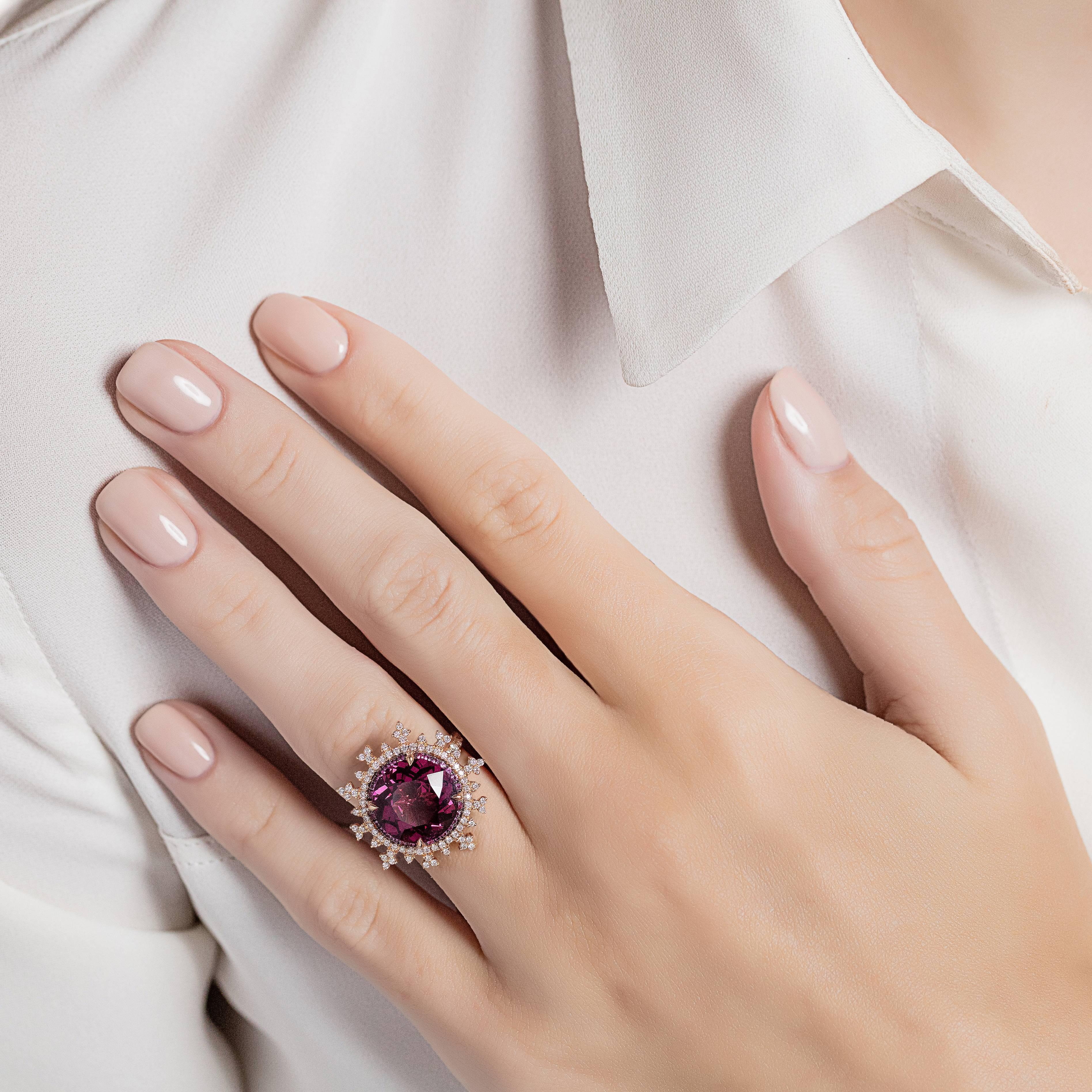 18K rose gold (5.0g), 1 round-cut rhodolite 7.00ct, 28 round-cut pink sapphires -.14ct.., 105 white round-cut diamonds 0.69ct.

An exquisite 18K rose gold and round-cut rhodolite and diamond fire flake ring. The rhodolite is surrounded by 105 white