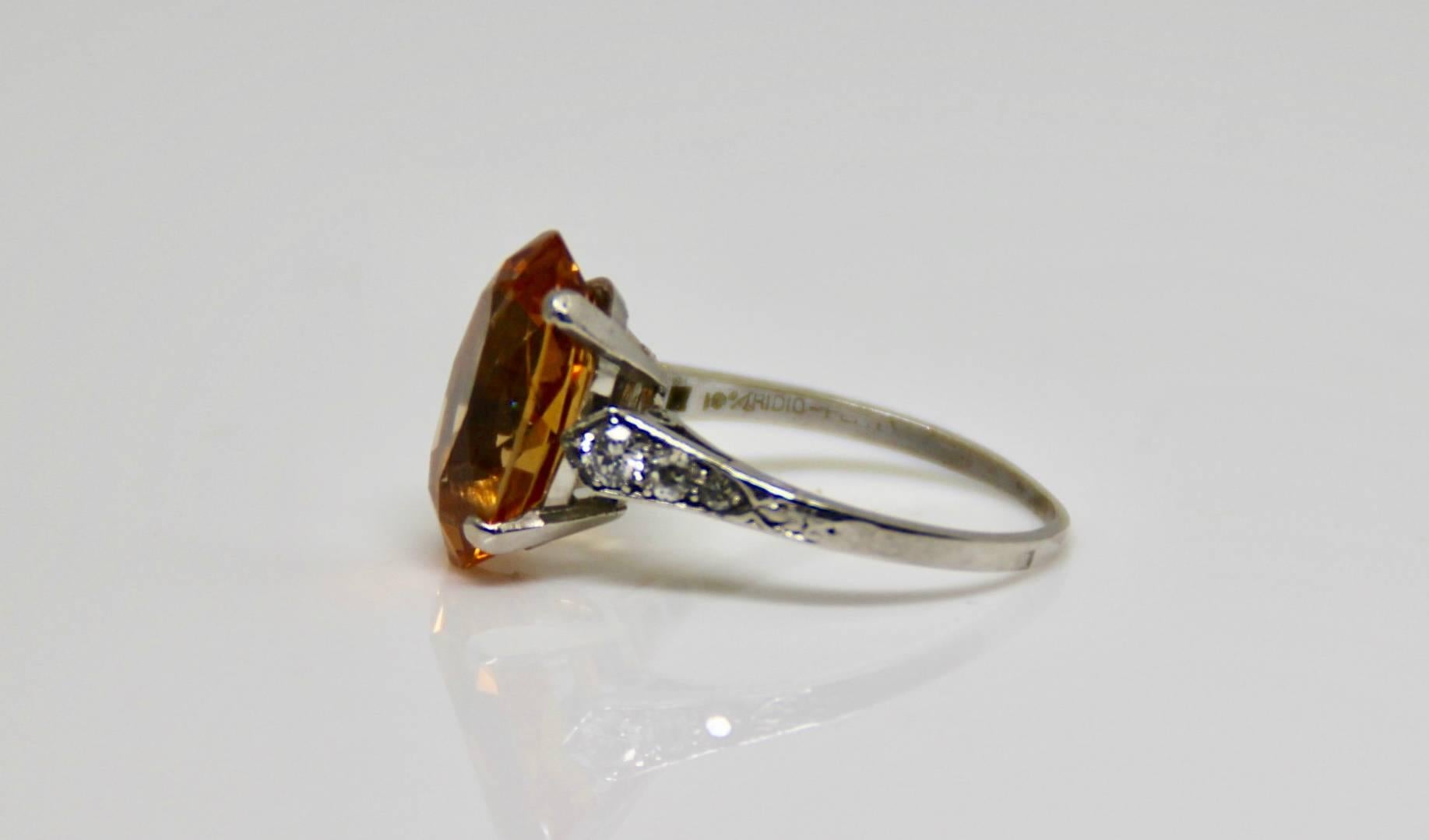 A fiery 8 carat Brazilian  (Imperial) Topaz an diamond ring. We believe the shank it older and in the 1940's a new collect was used. It has three diamonds on either side running down the shank. the two larger on either side are modern transitional