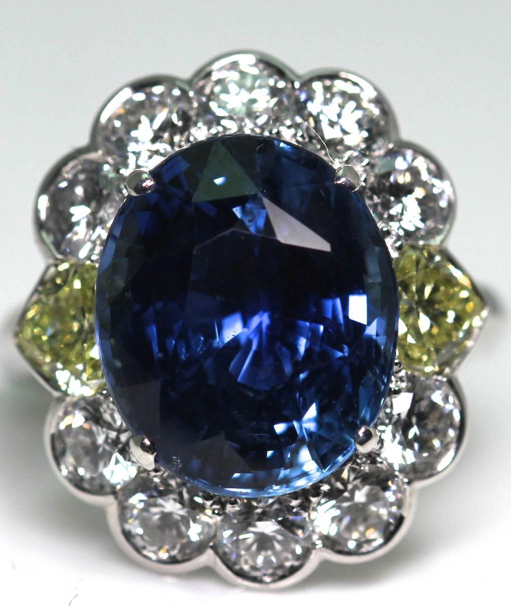 Natural Oval blue Sri Lankan Sapphire Ring weighing 9.99 cts set in a cluster diamond, accented with heart shape yellow diamonds mounted in white gold. The total weight of yellow diamonds 0.97cts, with 1.80cts of white diamonds. The sapphire is
