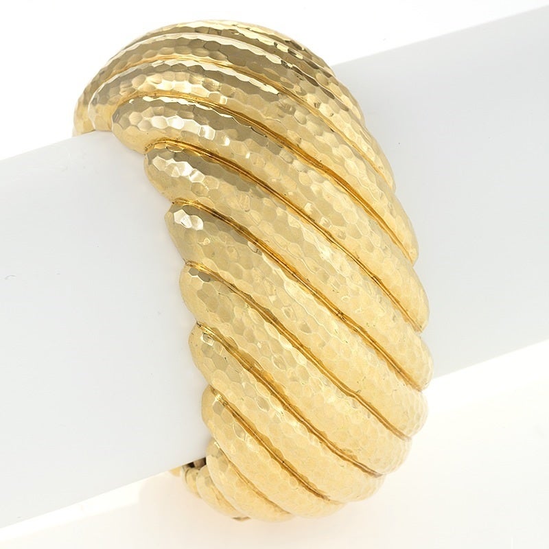 A Late-20th Century 18 karat gold cuff bracelet by Andrew Clunn. The cuff bracelet is composed of hammered and diagonally ribbed gold with a hinged open back.  Provenance:  Private Collection of Andrew Clunn. Circa 1980's. 

Andrew Clunn’s jewelry