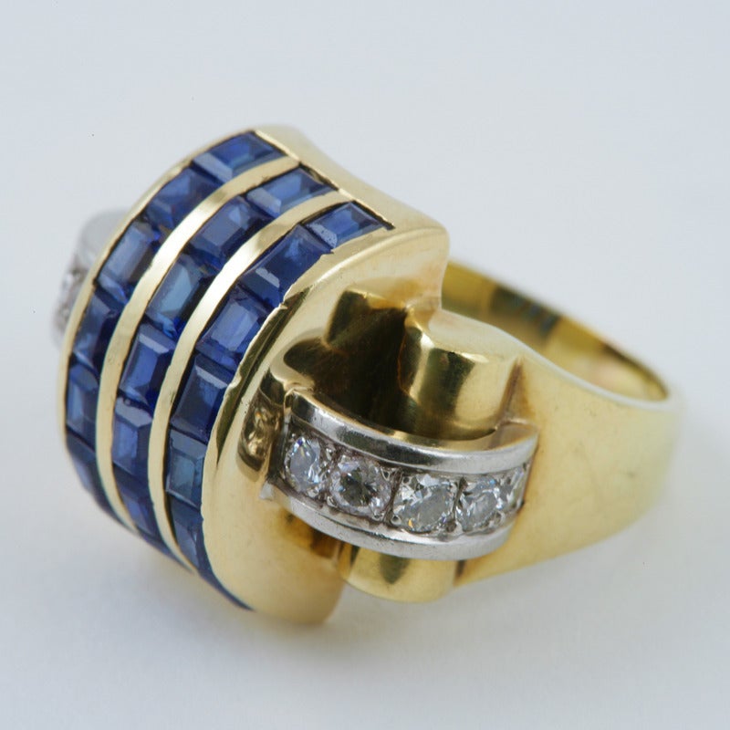 An American Retro 14 karat gold and platinum ring with sapphires and diamonds by Trabert & Hoeffer Mauboussin. The ring centers on 21 calibre-cut blue sapphires with an approximate total weight of 2.50 carats, with 10 round-cut diamonds with an