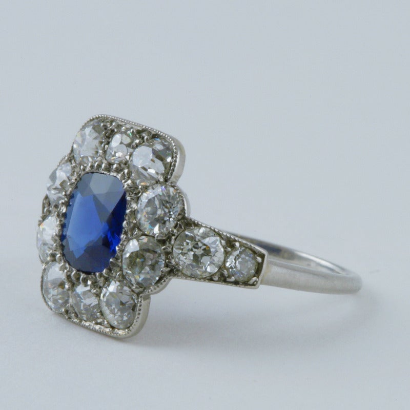 An Art Deco blue sapphire and diamond ring set in platinum. The ring centers on a cushion-cut blue sapphire from Cambodia (Pailin) that weighs 1.21 carats, and is framed with 14 old European-cut diamonds with an approximate total weight of 1.00