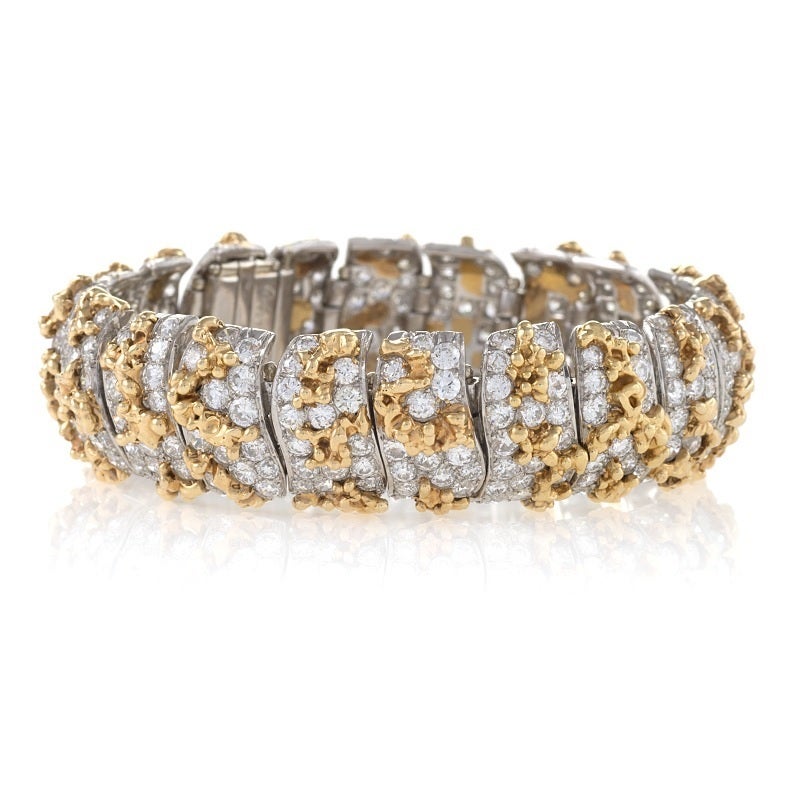 Set with sixteen carats of diamonds, this highly flexible gold and platinum bracelet is a 1960s creation of William Ruser. Designed as a series of curved, articulated links, the pavé-set round brilliant-cut diamonds are interspersed with heavily