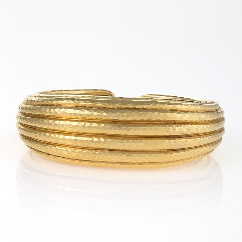 An American late-20th Century 18 karat gold hinged cuff bracelet by Andrew Clunn. The hinged, open back bracelet is tapered and is composed of eight horizontal rows of hammered gold.  

Provenance: Collection of Andrew Clunn. Circa 1980s.