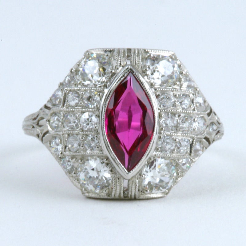 An Art Deco platinum ring with ruby and diamonds. The ring centers on a marquise-cut ruby with an approximate weight of 1.00 carat, surrounded by diamond-set platinum filigree with an approximate total weight of 1.10 carats.  Gemological Institute