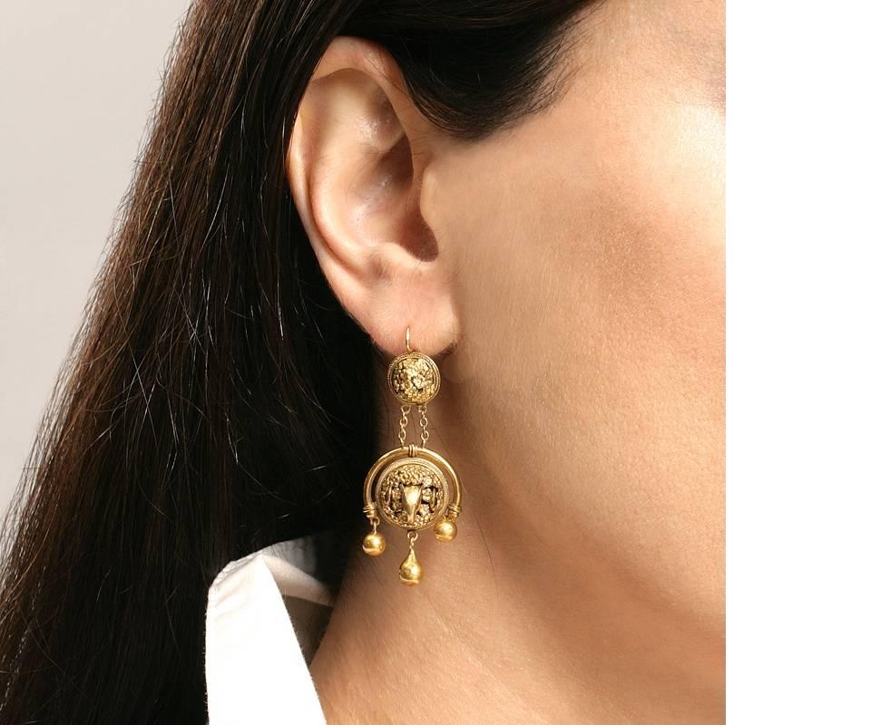 A pair of Etruscan Revival 18 karat gold girandole earrings.  The articulated earrings are designed in a dimensional classical motif of rams heads.  