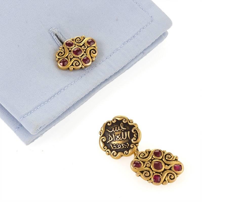 A pair of American Art Nouveau 18 karat gold cuff links with rubies by Marcus & Co. The Arabesque motif cuff links have 10 round rubies with an approximate total weight of 1.10 carats. The inscription on the back face in Arabic script translates to