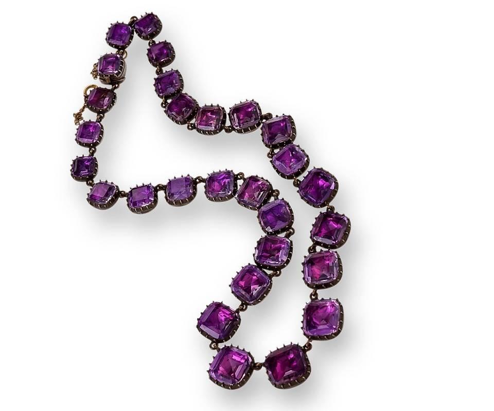 An English Georgian 9 karat gold and silver Rivière necklace with 28 cushion-cut, foil backed amethysts that graduate in size and are chain linked. (Safety chain added later.)

The rivière is a short (usually 14-16 inches) necklace simply composed