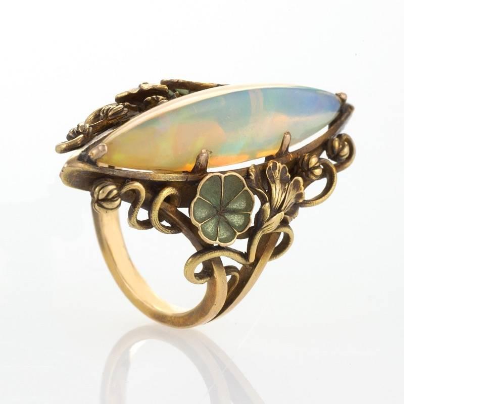 A French Art Nouveau 18 karat gold and plique-à-jour enamel ring with opal attributed to Georges Le Turcq. The ring has a long marquise opal set with floral and foliate motifs in gold, and plique-à-jour enamel lily pads.  Circa 1900.

Similar