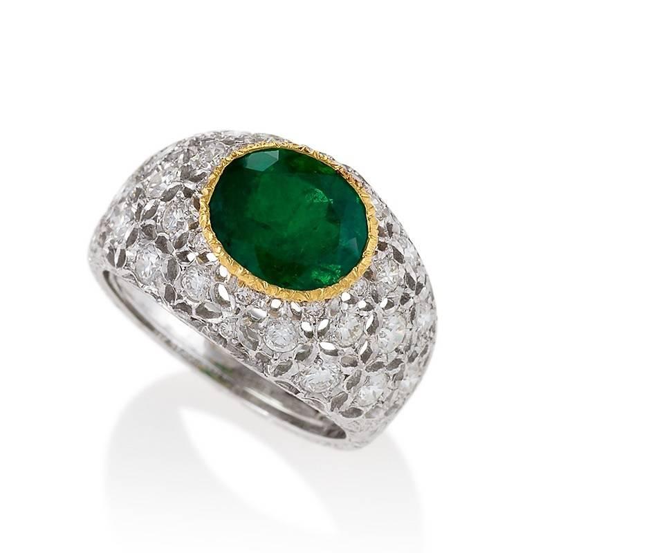 This Buccellati ring is set with a beautiful, two-carat oval-cut Colombian emerald in bi-color gold, highlighted by round brilliant-cut diamonds. Created by multiple techniques of hand piercing and engraving, the ring centers on this satiny green