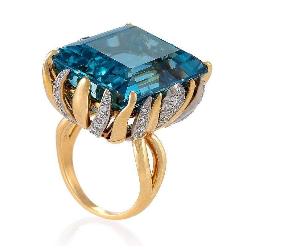 An American Mid-20th Century 18 karat gold and platinum ring with aquamarine and diamonds by William Ruser. The ring has a step-cut aquamarine with an approximate total weight of 33.30 carats, and 68 round brilliant-cut diamonds with an approximate