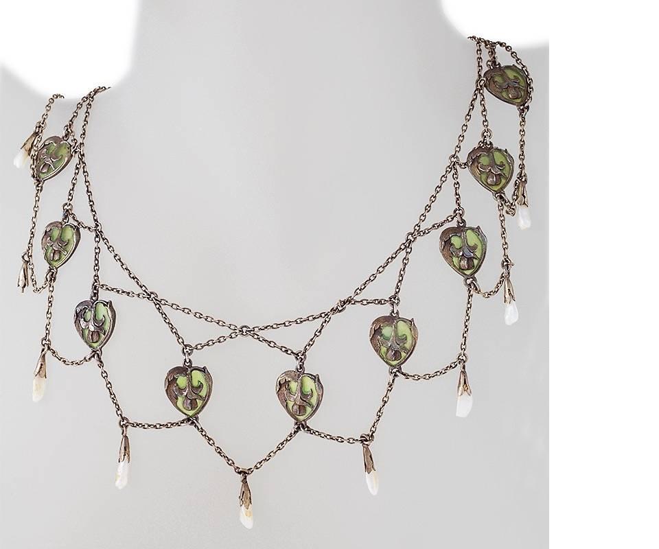 A French Art Nouveau silver and plique-à-jour enamel necklace with pearls. The necklace has 9 freshwater pearls and 10 floral plique-à-jour enamel plaques forming the festoon motif. Antique box. Circa 1900.

Signed, French control mark for silver.