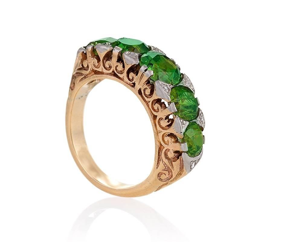 An American Antique 14 karat and platinum ring with demantoid garnets and diamonds. The classic  ring has 5 old European-cut demantoid garnets with an approximate total weight of 5.10 carats, and 10  rose-cut diamonds
with an approximate total