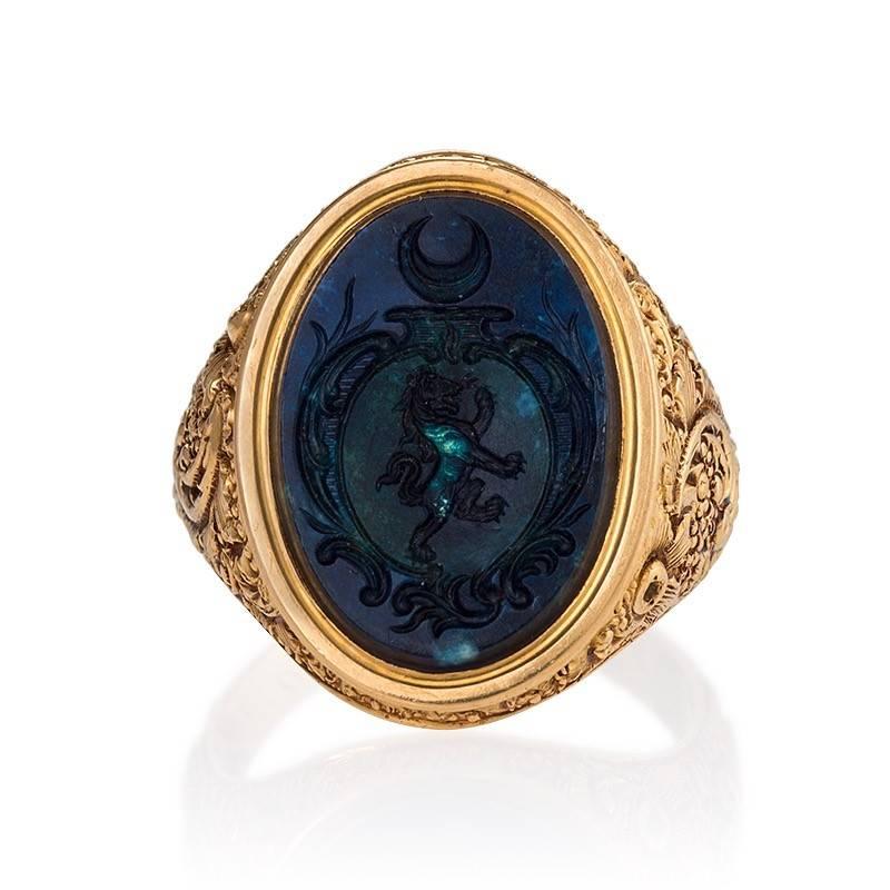 n English 18 karat gold ring with agate intaglio.  The shoulders of the ring are deeply carved in a modified foliate motif with pomegranate-like fruits and decorative vines. The agate intaglio crest is deeply carved with a lion and half moon. Circa