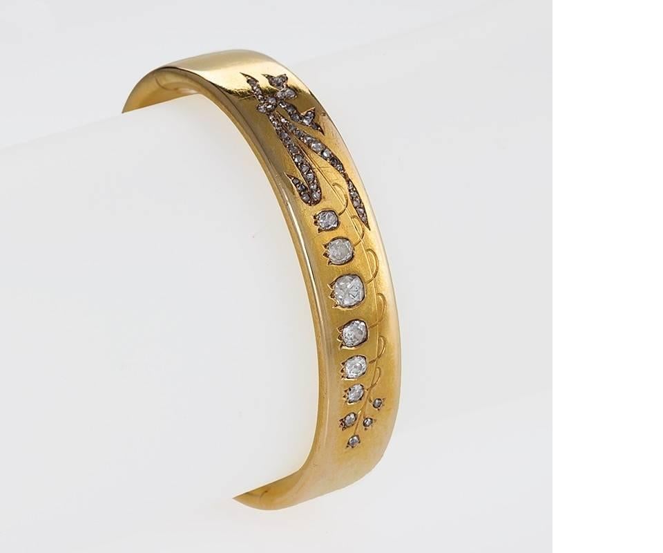 A French Antique 18 karat gold bangle bracelet with diamonds. The bangle bracelet has 7 old mine-cut diamonds 
and 49 rose-cut diamonds with an approximate total weight of 1.70 carats. The hinged bangle bracelet is decorated with lily of the valley