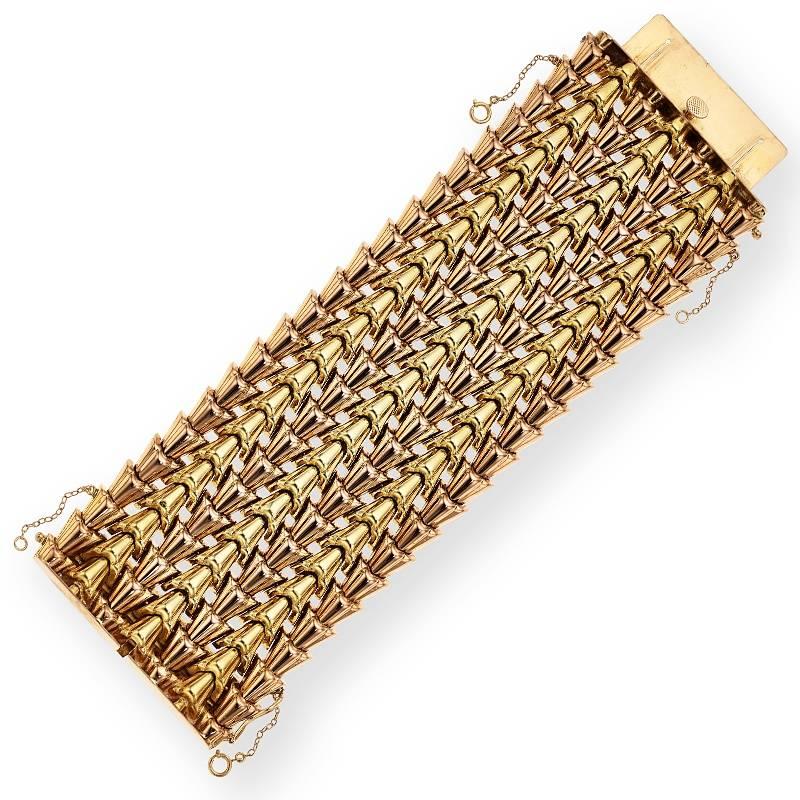 A Retro 18 karat rose and yellow gold bracelet. The exceptionally wide flexible bracelet is composed of alternating rose and yellow cone lines. The polished gold lines form the unique, very wide seven row Retro period pattern. Circa 1940's.

Signed,