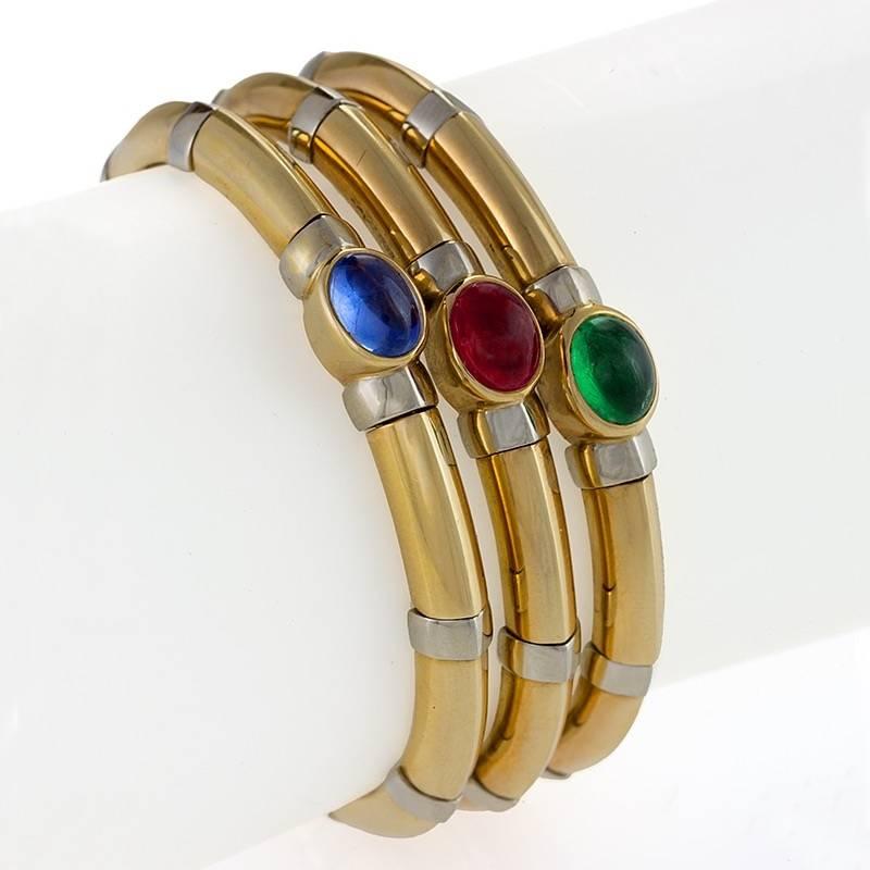 An Italian Mid-20th Century 18 karat polished white and yellow gold bangle bracelet with sapphire, ruby and emerald by Bulgari. The open-back flexible bracelet has 1 cabochon sapphire with an approximate total weight of 2.83 carats, 1 cabochon ruby