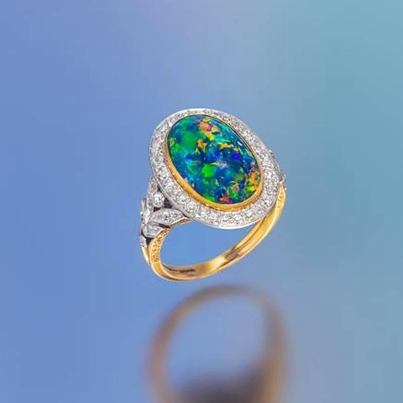 An American Edwardian platinum topped 18 karat  gold ring with black opal and diamonds by Marcus & Co.This ring centers on an oval black opal cabochon that measures 15.2 mm by 9.40 mm by 3.96 mm surrounded by 56 old European-cut diamonds with an