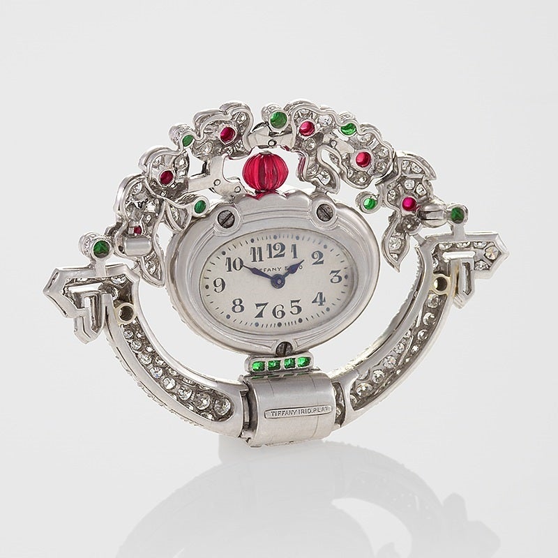 Dating from the classic Art Deco period, this Tiffany & Co. diamond, ruby, emerald and enamel brooch cleverly conceals a watch. Pavé-set with diamonds, the brooch is designed as a grand, stylized planter, patterned by channel-set diamond baguettes