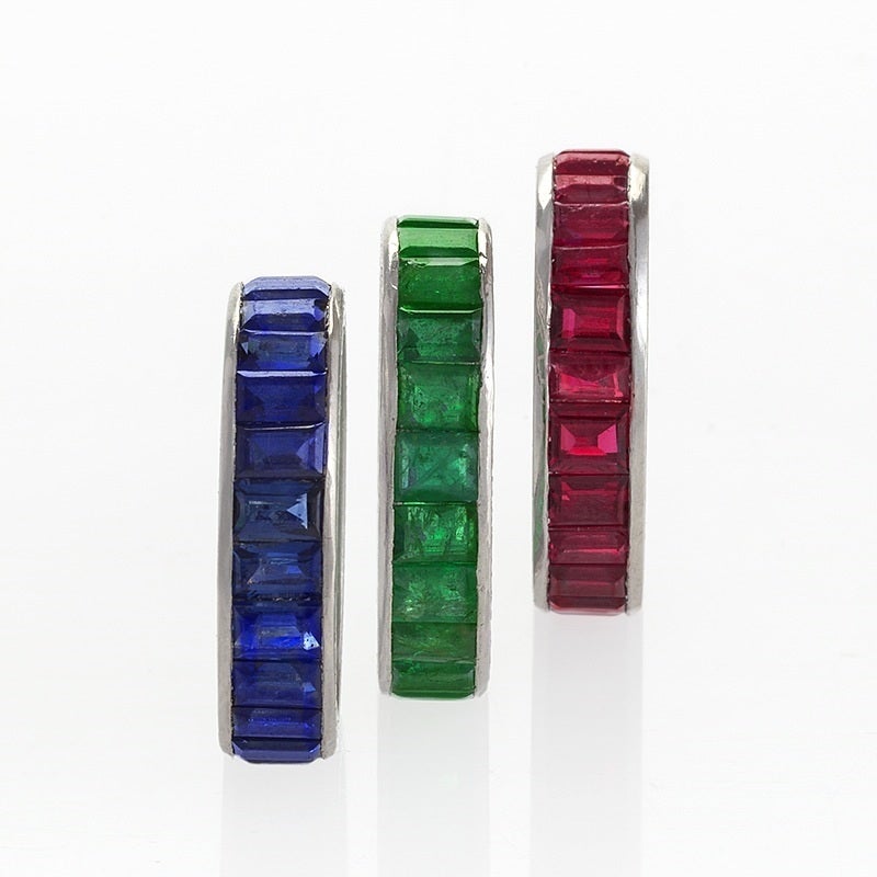 A set of three Mid-20th Century platinum rings, one with sapphires, one with emeralds and one with rubies. The rings have 23 rectangular-cut sapphires with an approximate total weight of 4.60 carats, 23 rectangular-cut emeralds with an approximate