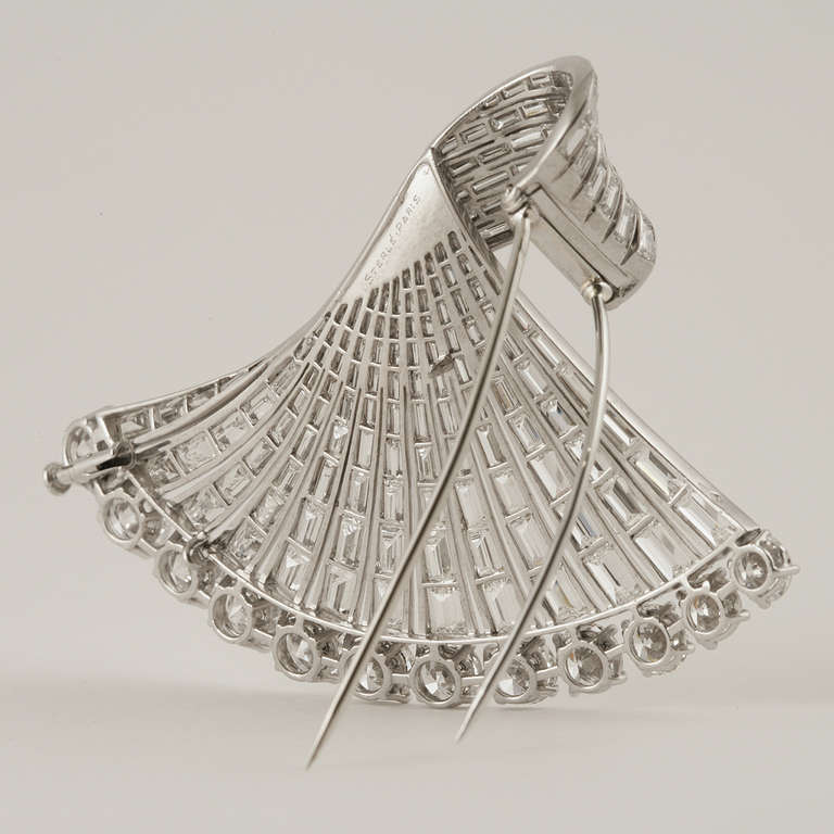 A French Mid-Century diamond and platinum brooch by Pierre Sterlé. This brooch features a stylized fan with a decorated edge of 12 round-cut diamonds with an approximate total weight of 12.60 carats, and a swirl of 168 baguette diamonds that have