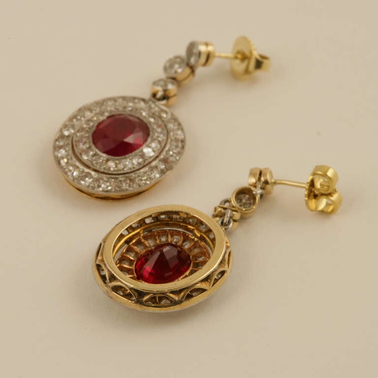 A pair of Edwardian platinum, ruby and diamond earrings. The earrings feature 2 oval Burmese rubies with an approximate total weight of 3.95 carats, that are surrounded by 90 old mine-cut diamonds with an approximate total weight of 2.15 carats. The