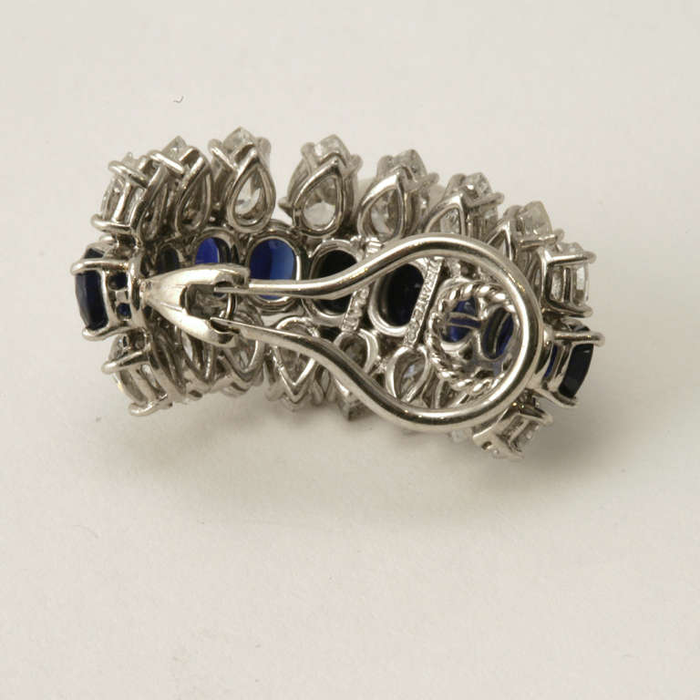 A pair of Mid-20th Century platinum earrings with sapphires and diamonds by Tiffany & Co. The earrings have a center row of 18 oval-cut sapphires with an approximate total weight of 10.20 carats, and 32 pear-cut diamonds with an approximate total