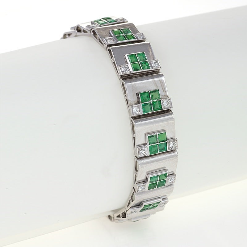 A French Retro 18 karat gold and platinum bracelet with emeralds and diamonds attributed to Rubel Frères. The bracelet has 64 square-cut emeralds with an approximate total weight of 8.30 carats, and 32 old European-cut diamonds with an approximate